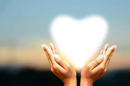 Womans hands holding up a heart shaped light.