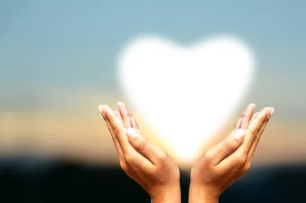 Womans hands holding up a heart shaped light.