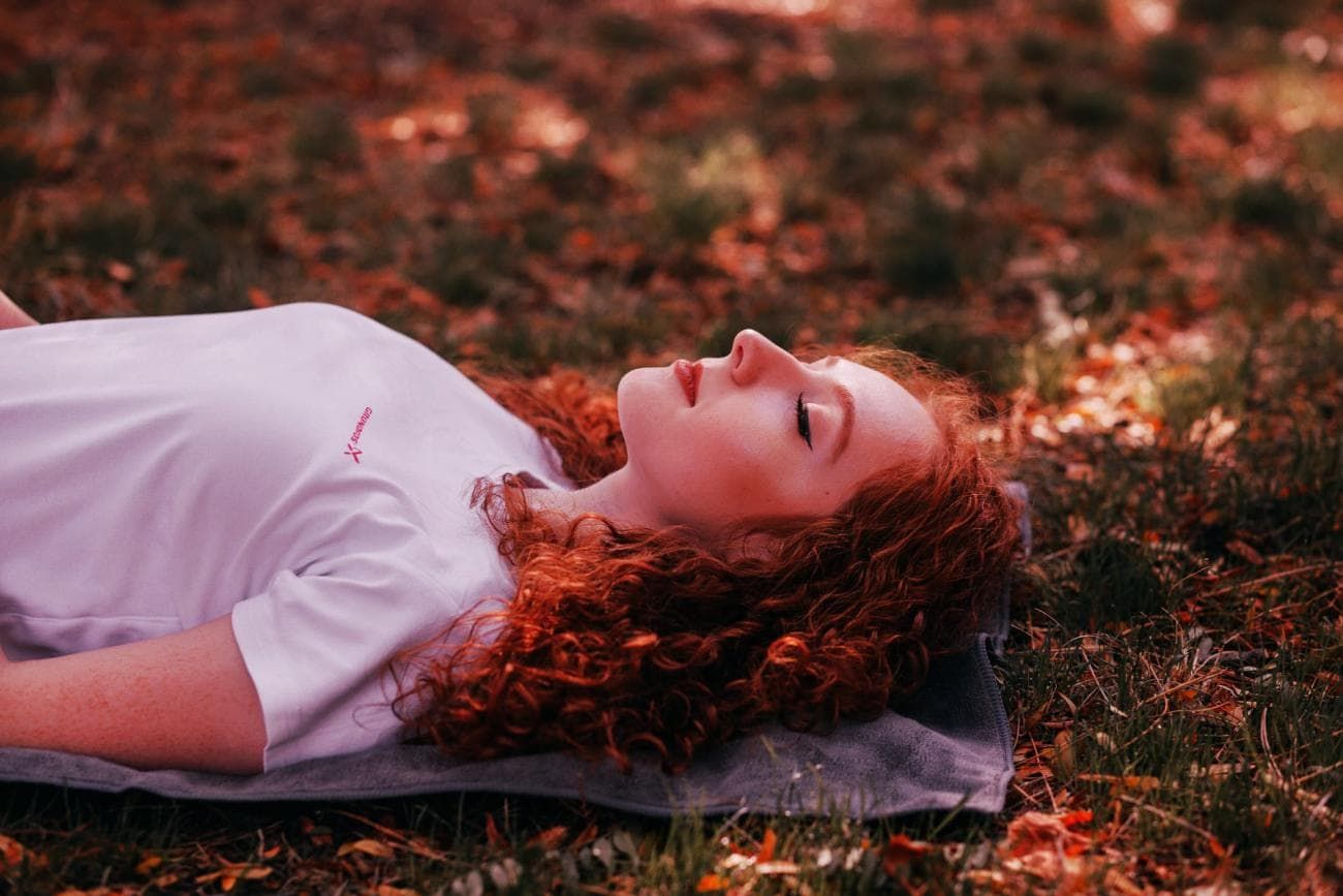 Woman with long red hair lying in leaves
