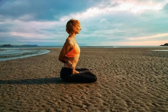 Woman meditating on the beach