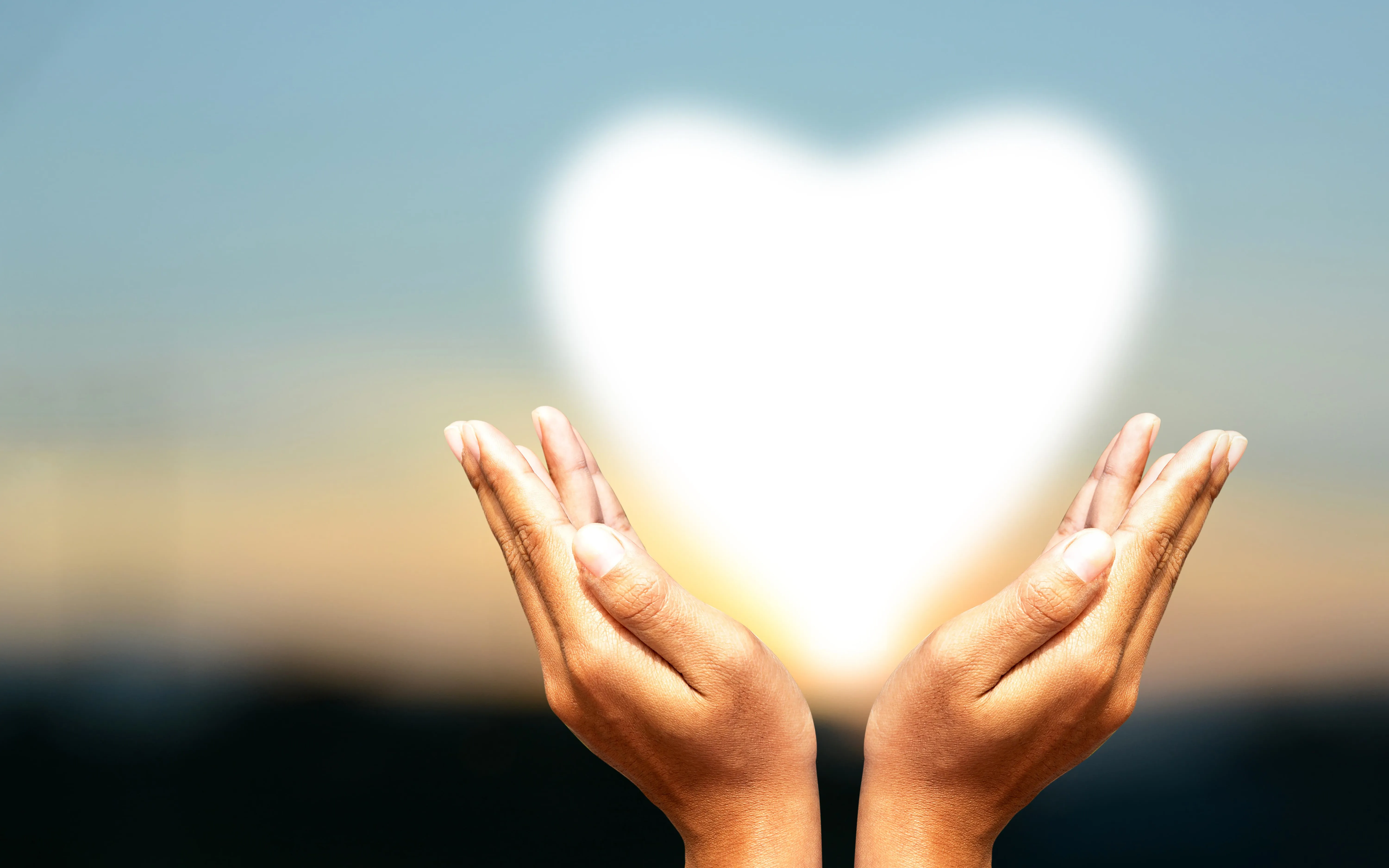 Womans hands holding up a heart shaped light.