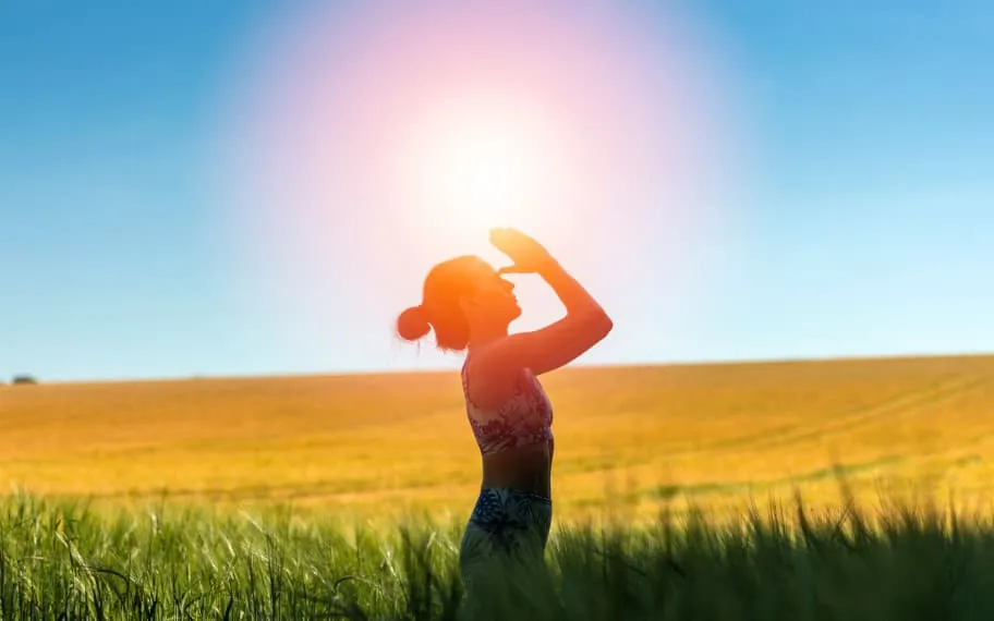 Silhouette of woman in field worshipping the sun